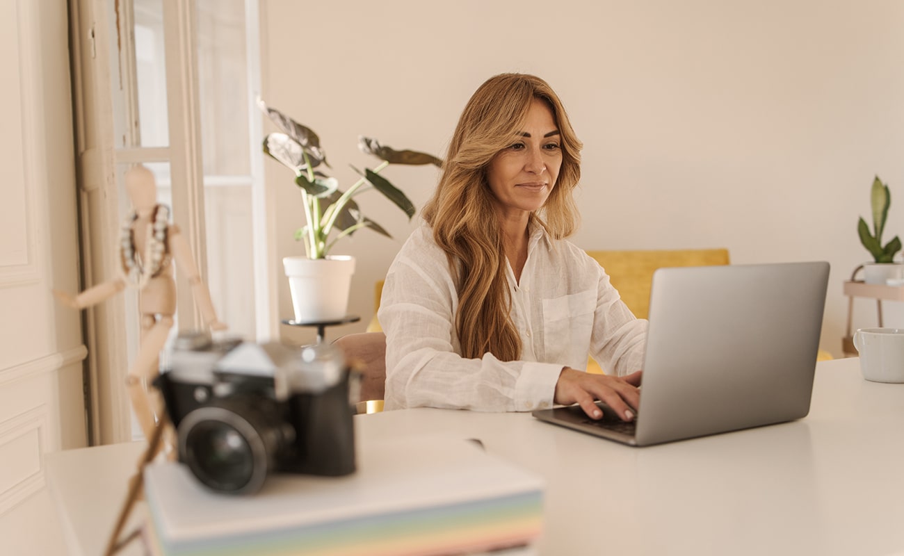 pretty-caucasian-adult-woman-working-project-notebook-while-sitting-desk-day-technological-device-concept-min